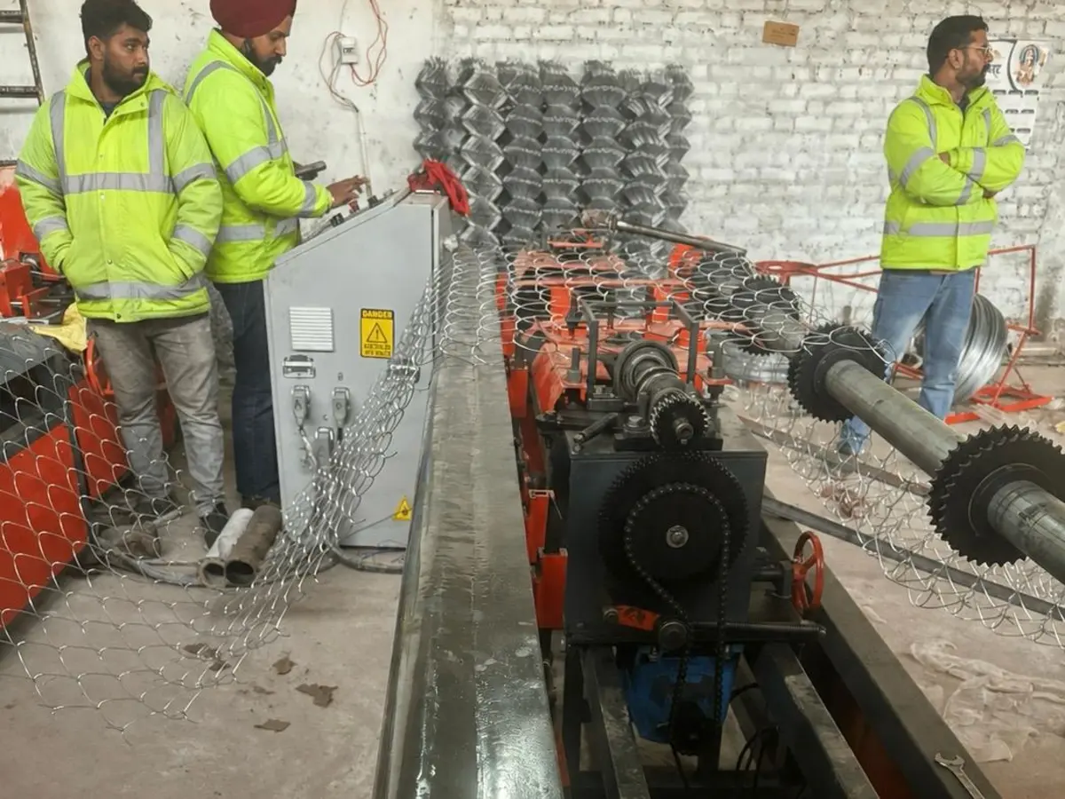 AK Industries team operating a chain-link weaving machine on the production floor